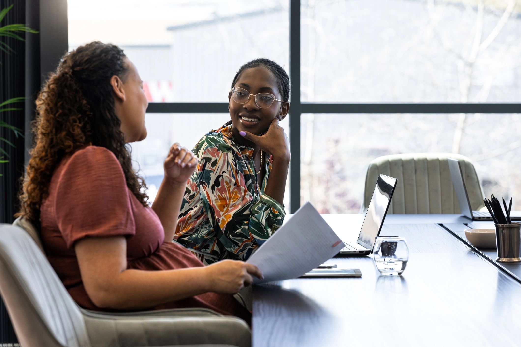 Two professionals in a supportive mentoring conversation at a conference table